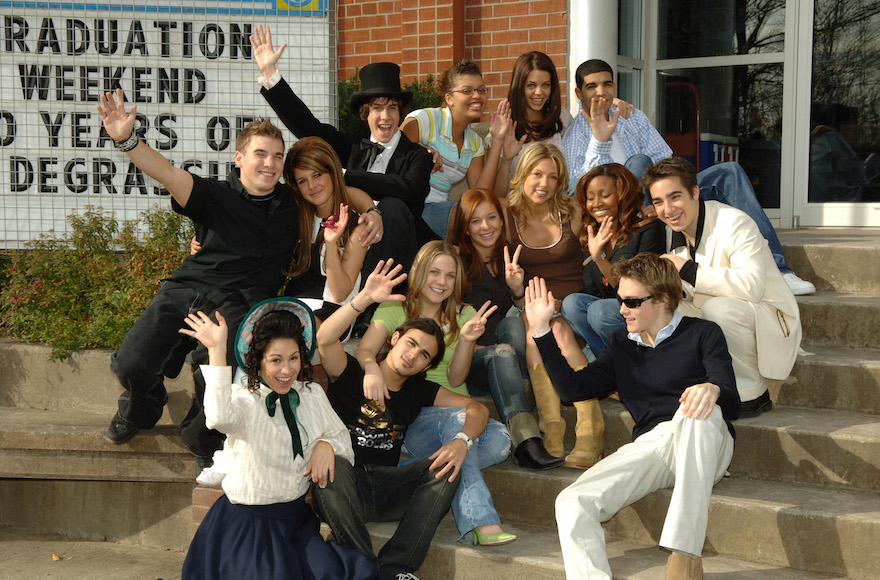 The cast of 'Degrassi: Next Generation' celebrating their 100th episode at the Degrassi High School Set in Toronto, Canada. Drake is at the top right, Lauren Collins is in center in green shirt, Jake Goldsbie is on right in white jacket, Shane Kippel is far left in black shirt. (George Pimentel/WireImage)